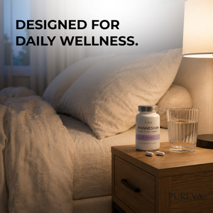 Pureva Magnesium bottle on wooden bedside table with water glass, capsules, lamp in cozy bedroom sleep wellness setting