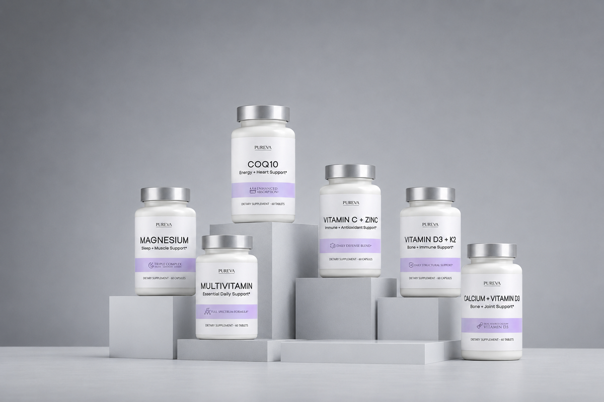 Six white supplement bottles with silver caps and lavender labels from the brand RUVU, arranged on gray geometric pedestals against a neutral gray background. The bottles include CogID, Magnesium, Multivitamin, Vitamin C + Zinc, Vitamin D3 + Zinc, and X202 Vitamin D.